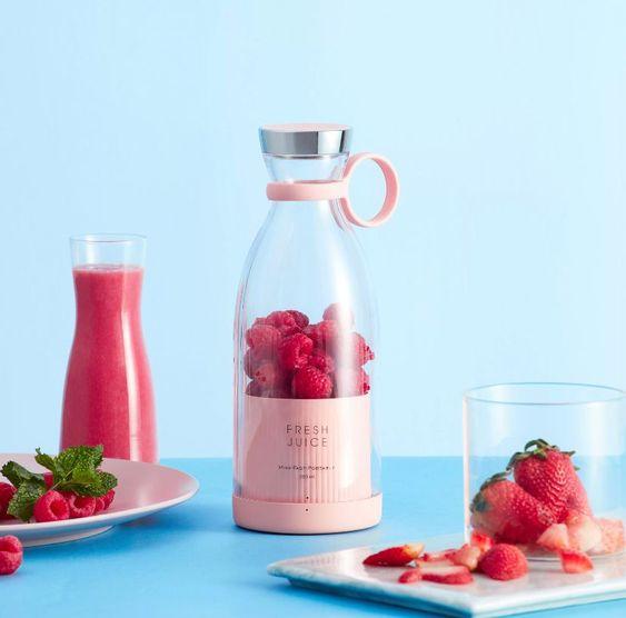 Pink portable blender filled with raspberries